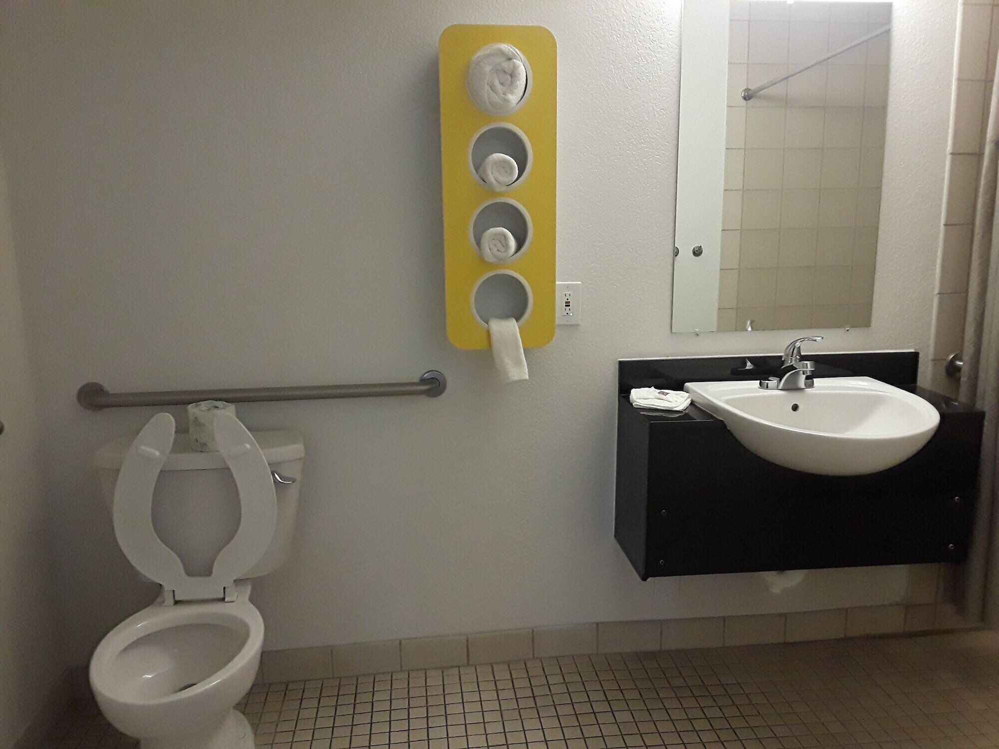 A bathroom with a toilet, a sink, and a mirror.