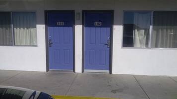 A building with two doors labeled 101 and 102, a yellow curb, and a parked car.