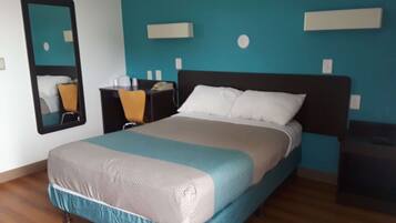 A neatly arranged bedroom with a bed, a desk, and a chair.