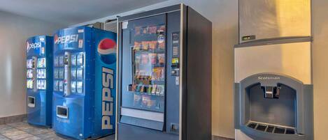 Tres máquinas expendedoras de bebidas, una etiquetada como 'Pepsi' y otra como 'Scotsman', en un pasillo.