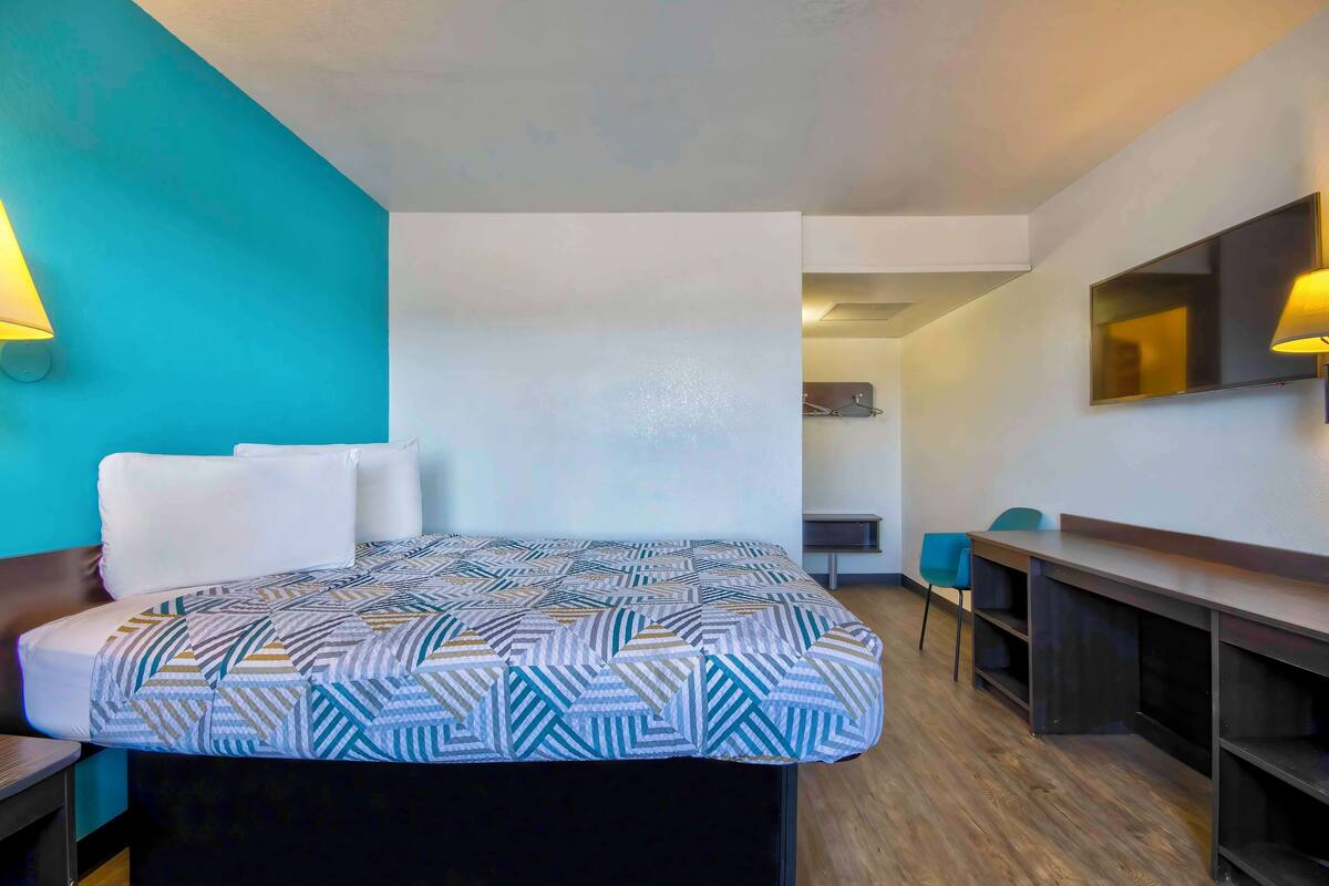 Una habitación de hotel con cama, escritorio, silla y televisión.