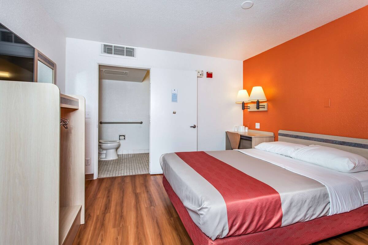 A hotel room with a bed, a desk, a chair, a wardrobe, and a bathroom.