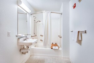 Un baño moderno con lavamanos blanco, espejo y zona de ducha.