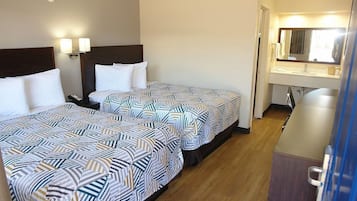 Une chambre d’hôtel avec deux lits, une salle de bain avec un miroir et un bureau.