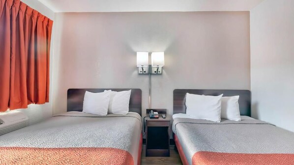 A hotel room with two beds, a nightstand, a lamp, and a window with curtains. - Motel 6 Gallup, NM (Gallup)