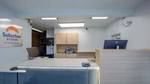 Ein Empfangsbereich mit Schreibtisch, Computer und einem Schild für Suburban Studios by Choice Hotels.