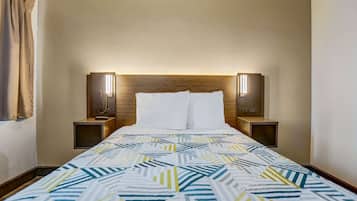 A hotel room with a bed, two bedside tables, a nightstand, a headboard, and two wall-mounted lamps.