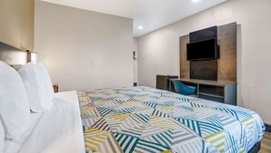 Habitación de hotel con una cama grande, un televisor montado en la pared y un escritorio con una silla.
