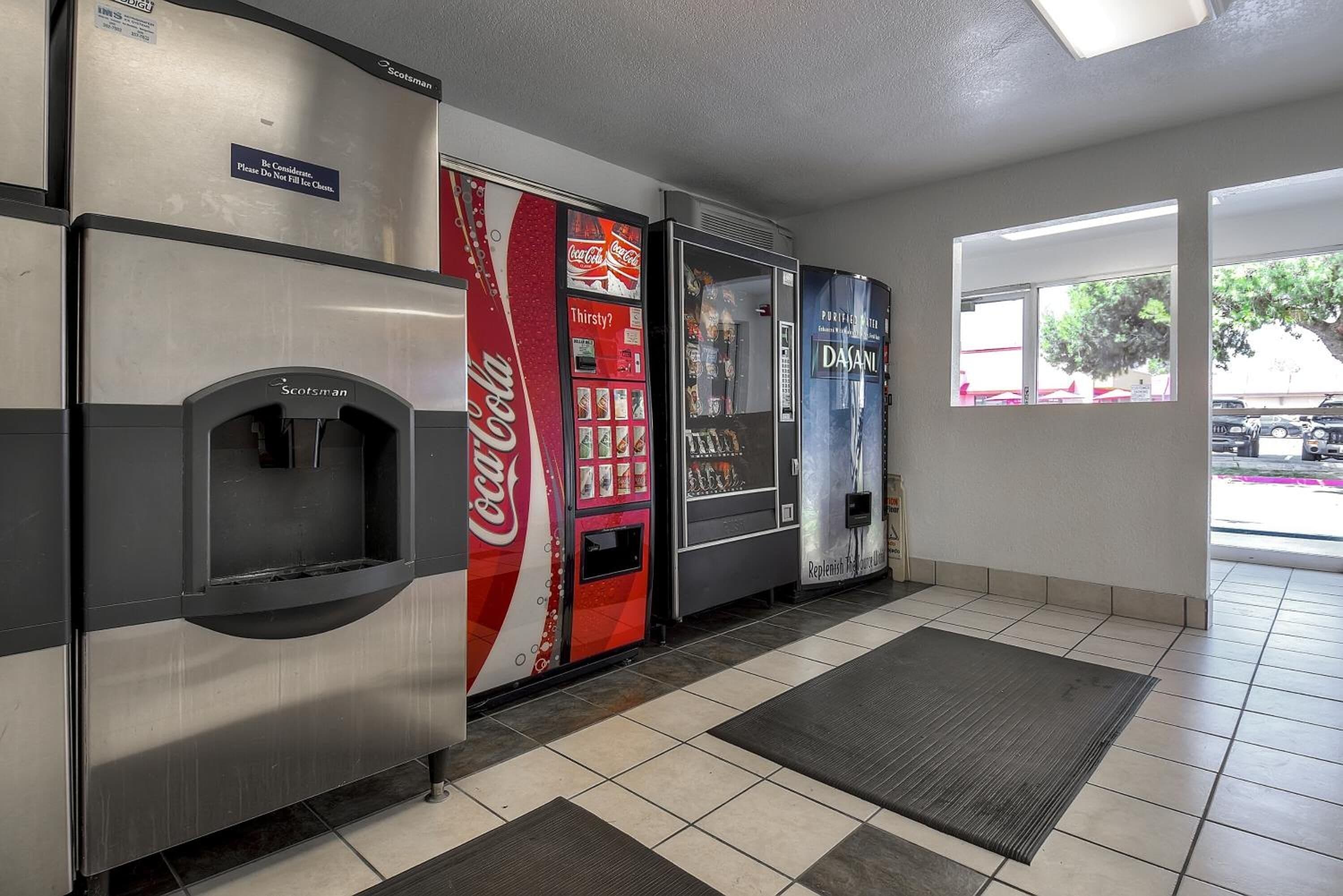A vending area with a Coca-Cola machine, a Dasani water dispenser, and a refrigerated section.