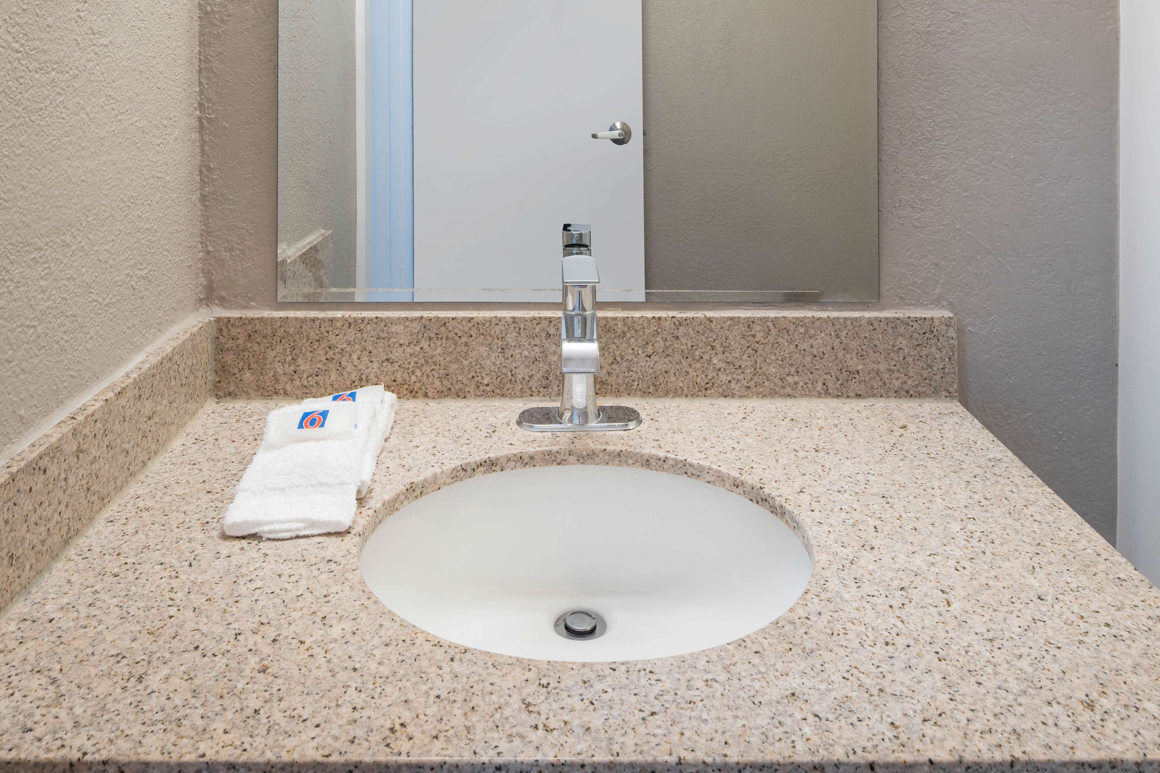A bathroom with a granite countertop, a white sink, and a towel.
