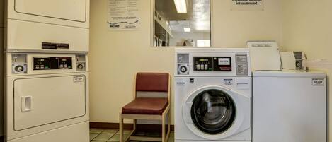 Un cuarto de lavandería con lavadora, secadora y zona para doblar la ropa.