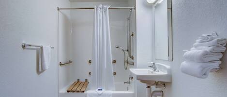 A bathroom with a shower, a sink, and a towel rack.