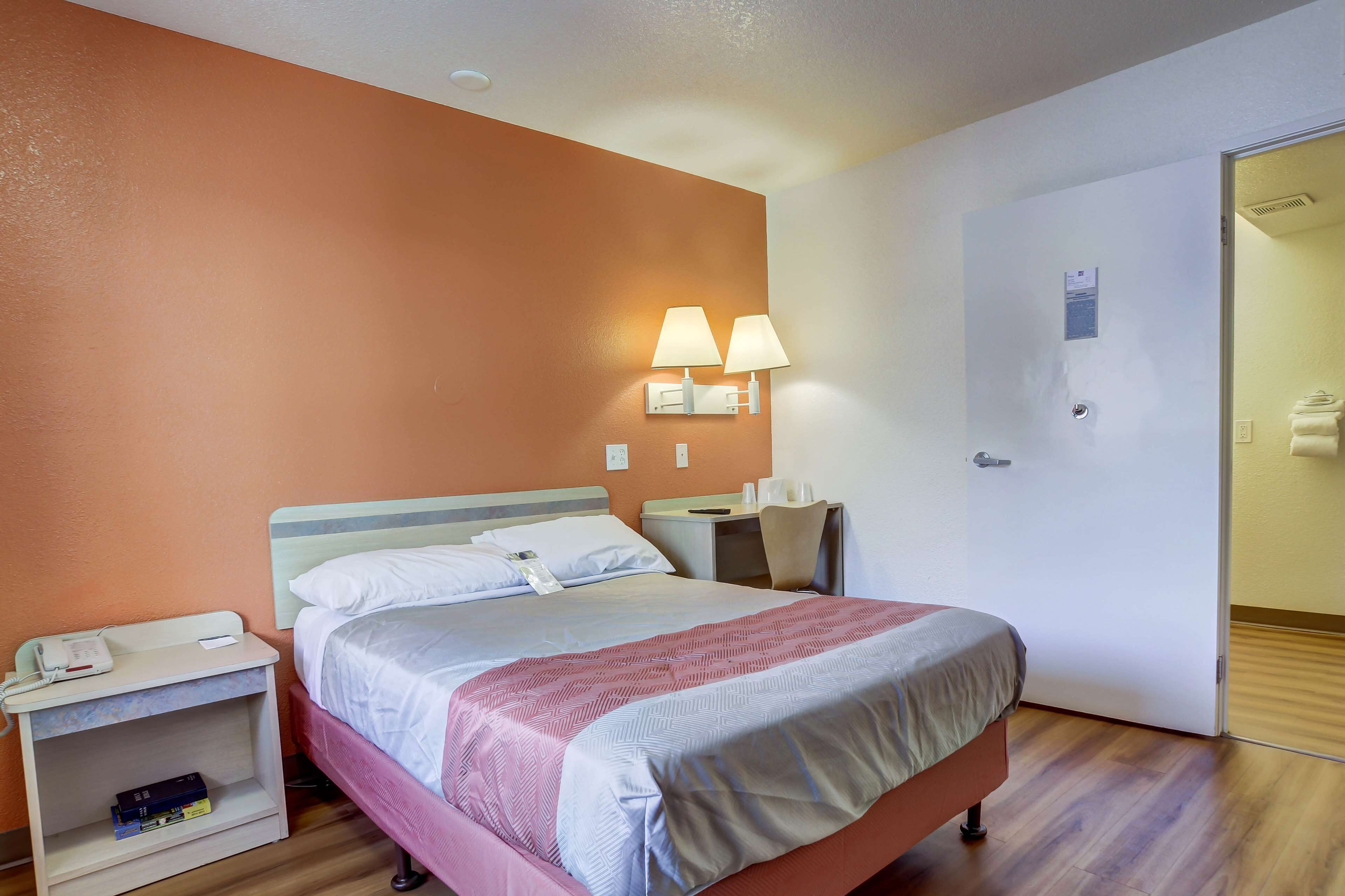 Una habitación de hotel con cama, mesitas de noche, escritorio y una silla.