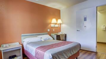 Una habitación de hotel con cama, mesitas de noche, escritorio y una silla.