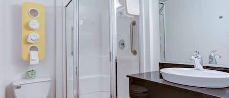 A modern bathroom with a glass-enclosed shower, a white toilet, and a sink with a dark countertop.