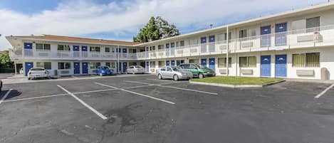 A motel with multiple floors, a parking lot, and several cars parked in front.