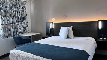 A modern hotel room with a large bed, a desk, and a chair.