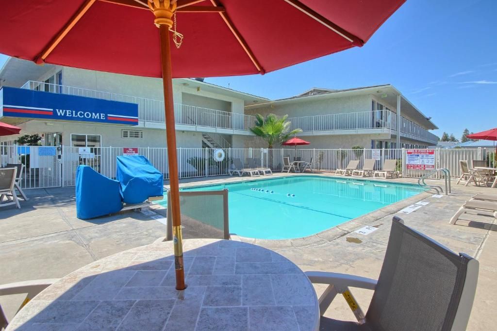 A pool area with a 'WELCOME' sign, lounge chairs, and a covered seating area.
