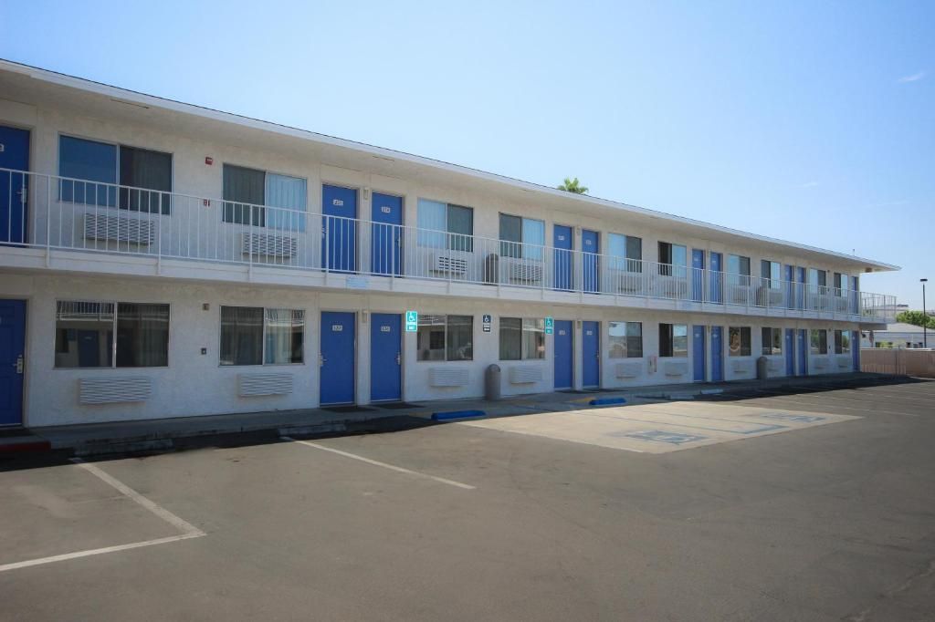 Un motel con una fila de habitaciones, cada una con un balcón y una puerta azul.