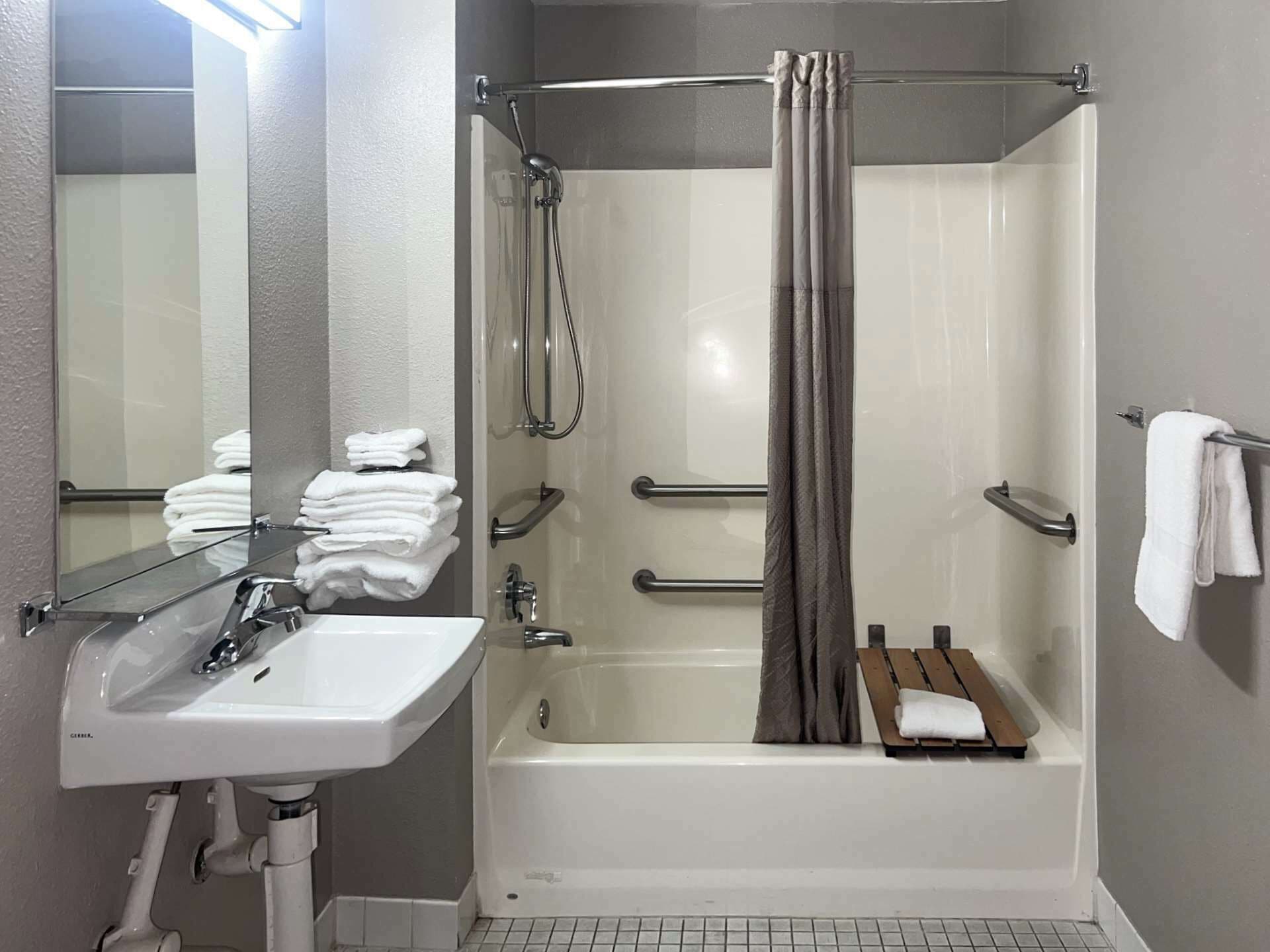 A modern bathroom with a white sink, a bathtub, and a shower curtain.