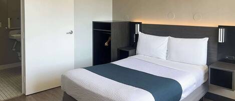 A hotel room with a large bed, a wardrobe, a bedside table, and a nightstand.
