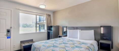 Habitación de hotel con una cama grande, un escritorio, una silla, una ventana con vistas y una puerta con cerradura.