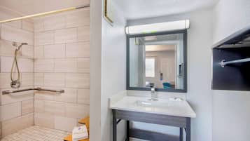 Een moderne badkamer met een inloopdouche, een witte wastafel en een grote spiegel.