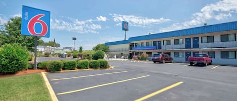 A motel with a blue and white exterior, a parking lot with marked spaces, and a clear sky.