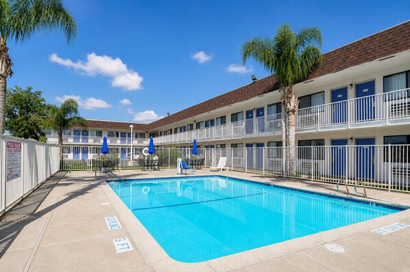 A hotel with a swimming pool, multiple balconies, and a fenced pool area. - Value Stay Inn Lost Hills (Lost Hills)