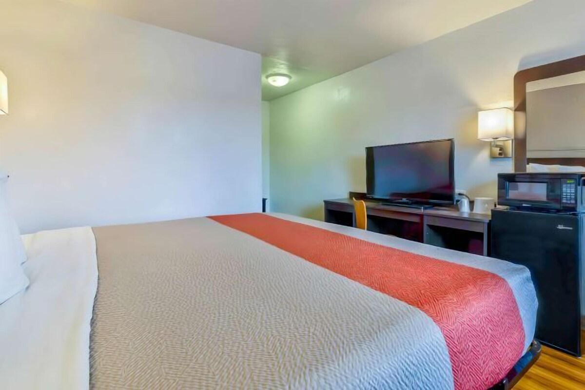 Habitació d'hotel amb un llit, una taula de treball, una televisió i un microones.