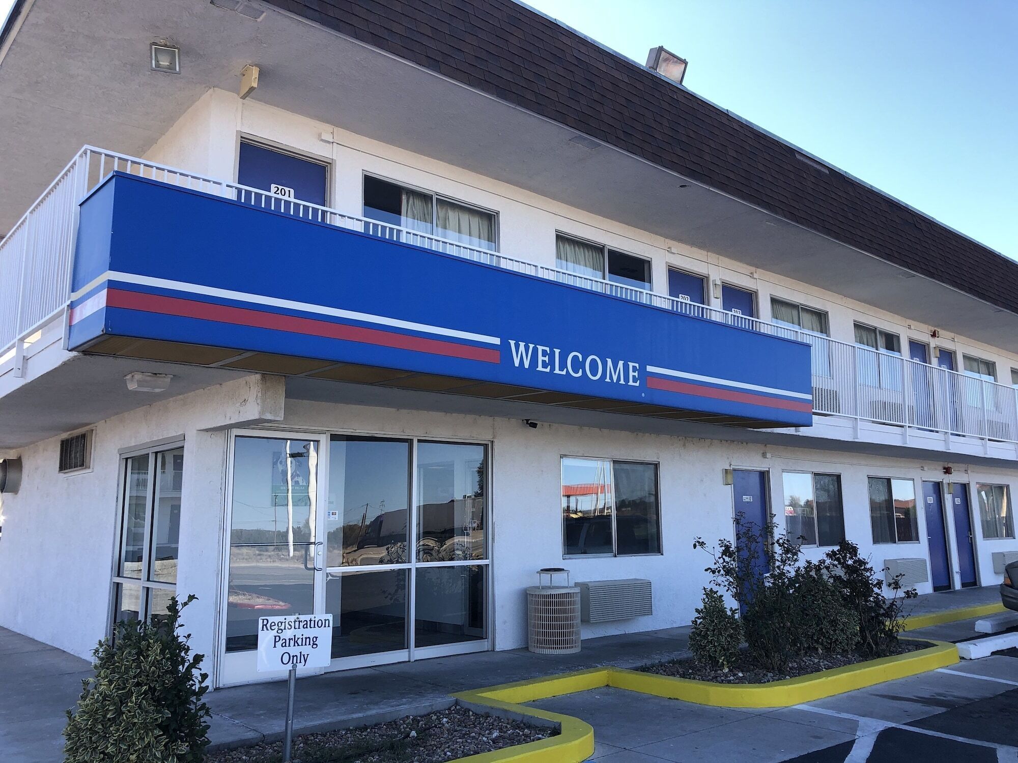 A building with a 'WELCOME' sign, registration parking, and a balcony.