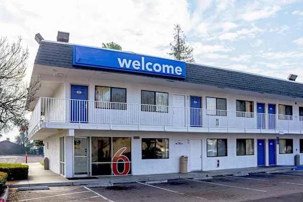 A motel with a 'welcome' sign, a number '6' sign, and a parking lot. - Motel 6 Porterville, CA (Porterville)