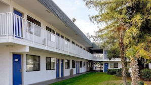 A motel with a central courtyard, multiple balconies, and a well-maintained lawn.