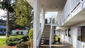 A building with a central staircase, a covered walkway, and a row of windows on the ground floor.