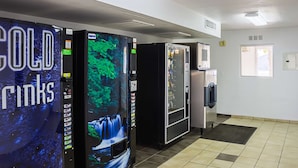A commercial kitchen with three refrigerators and a vending machine.