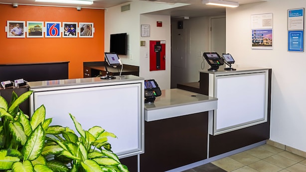 A reception area with a counter, a fire alarm, and a wall-mounted television.