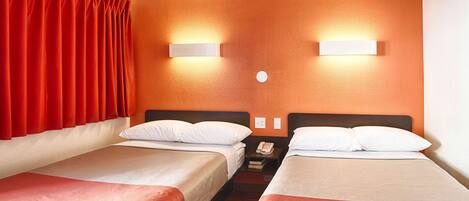 A hotel room with two single beds, a nightstand with a phone, and a wall-mounted light fixture.