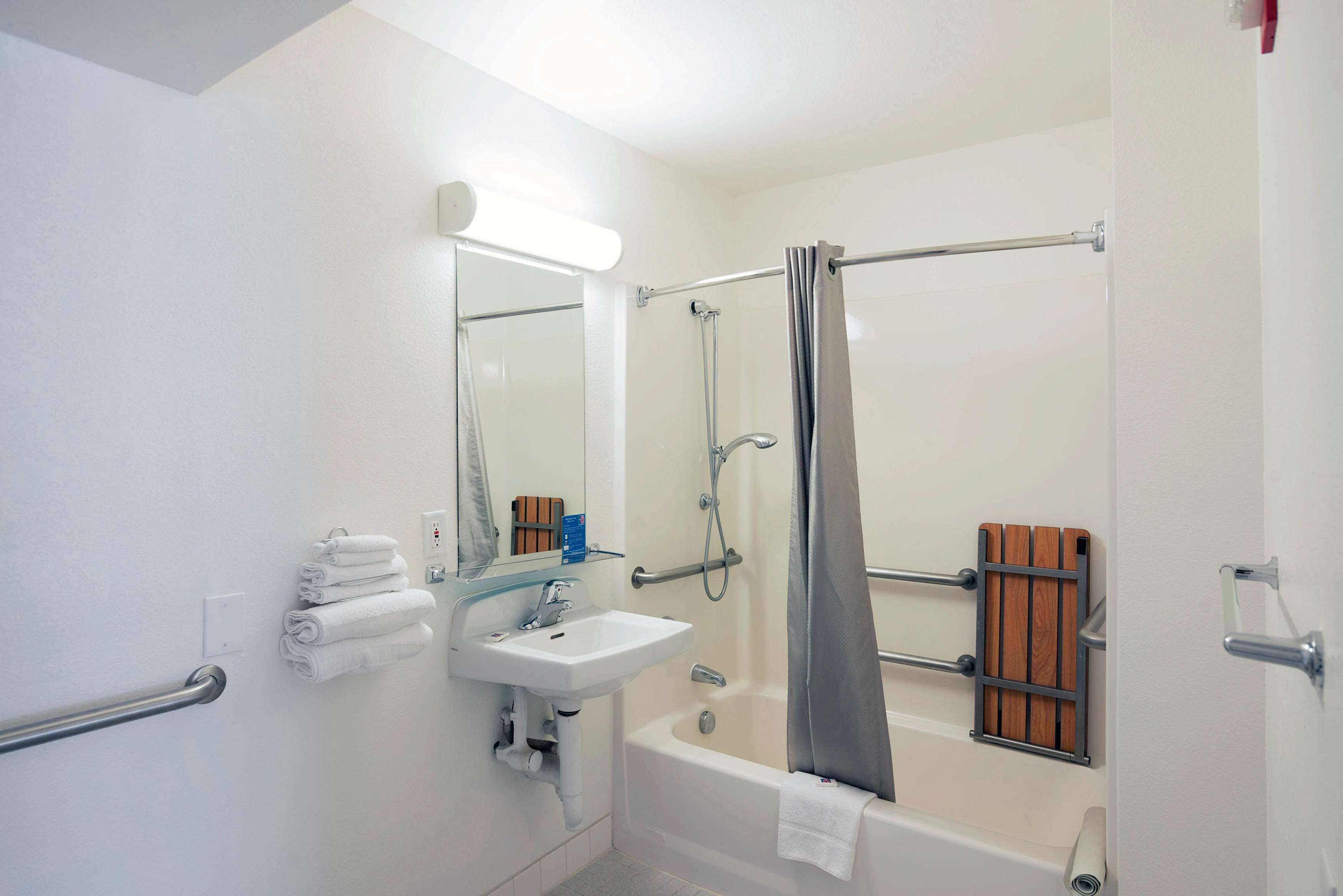 A bathroom with a sink, mirror, towel rack, shower, and bathtub.