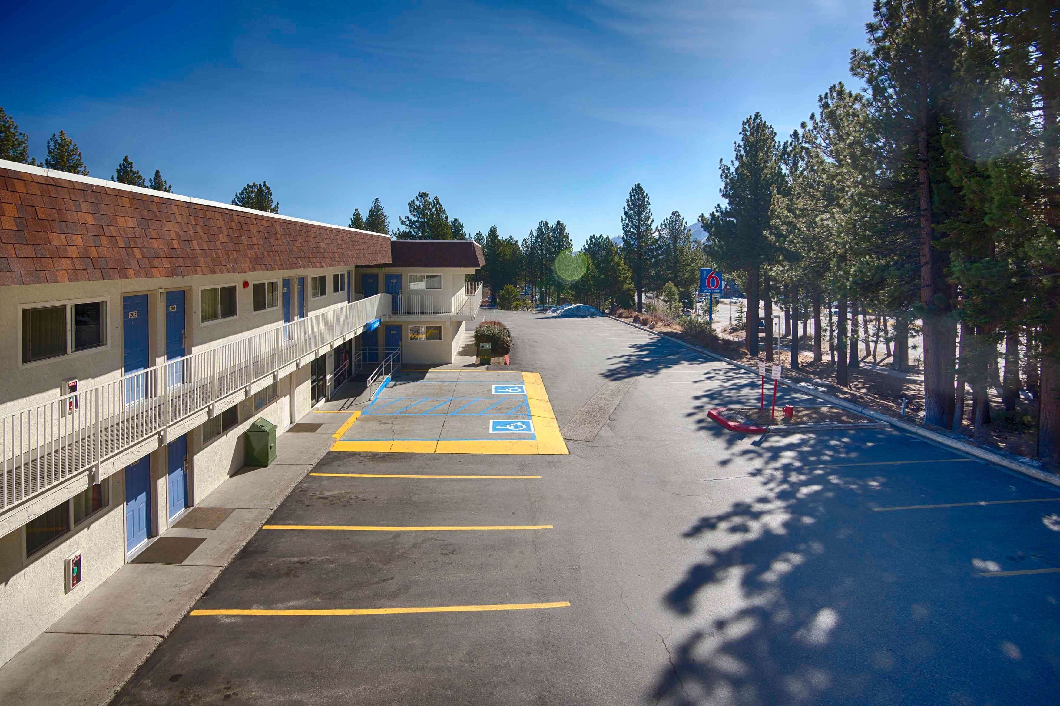 A motel with a parking lot, a building with multiple doors, and a clear sky.