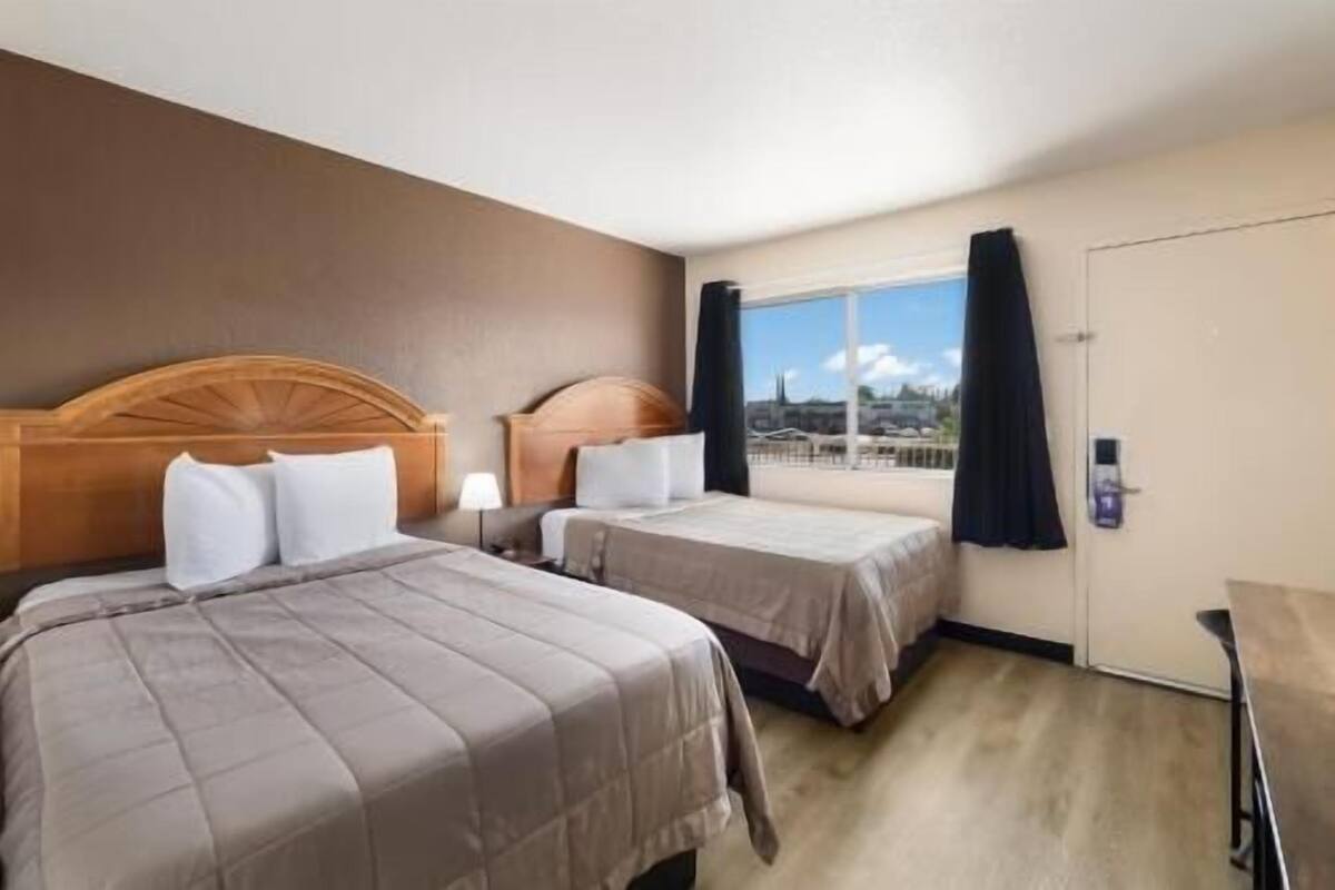 Une chambre d’hôtel avec deux lits, une fenêtre donnant sur un beau paysage et une porte dotée d’une poignée.