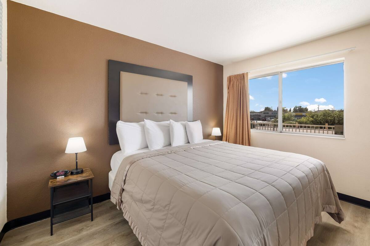 Une chambre d’hôtel avec un grand lit, une table de chevet avec une lampe et une fenêtre donnant sur l’extérieur.