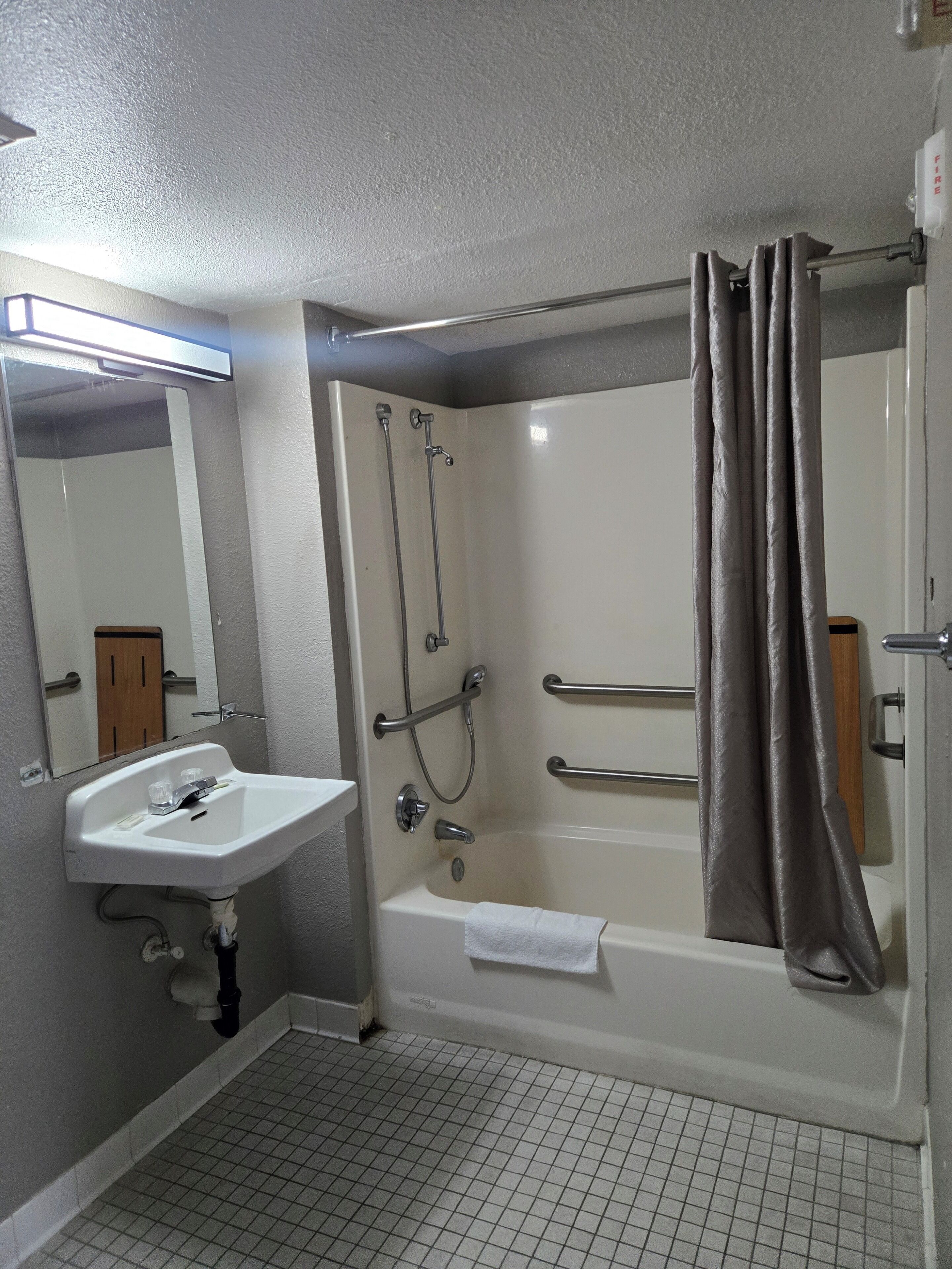 Ein Badezimmer mit weißem Waschbecken, einer Badewanne mit Duschbrause und einem Spiegel.