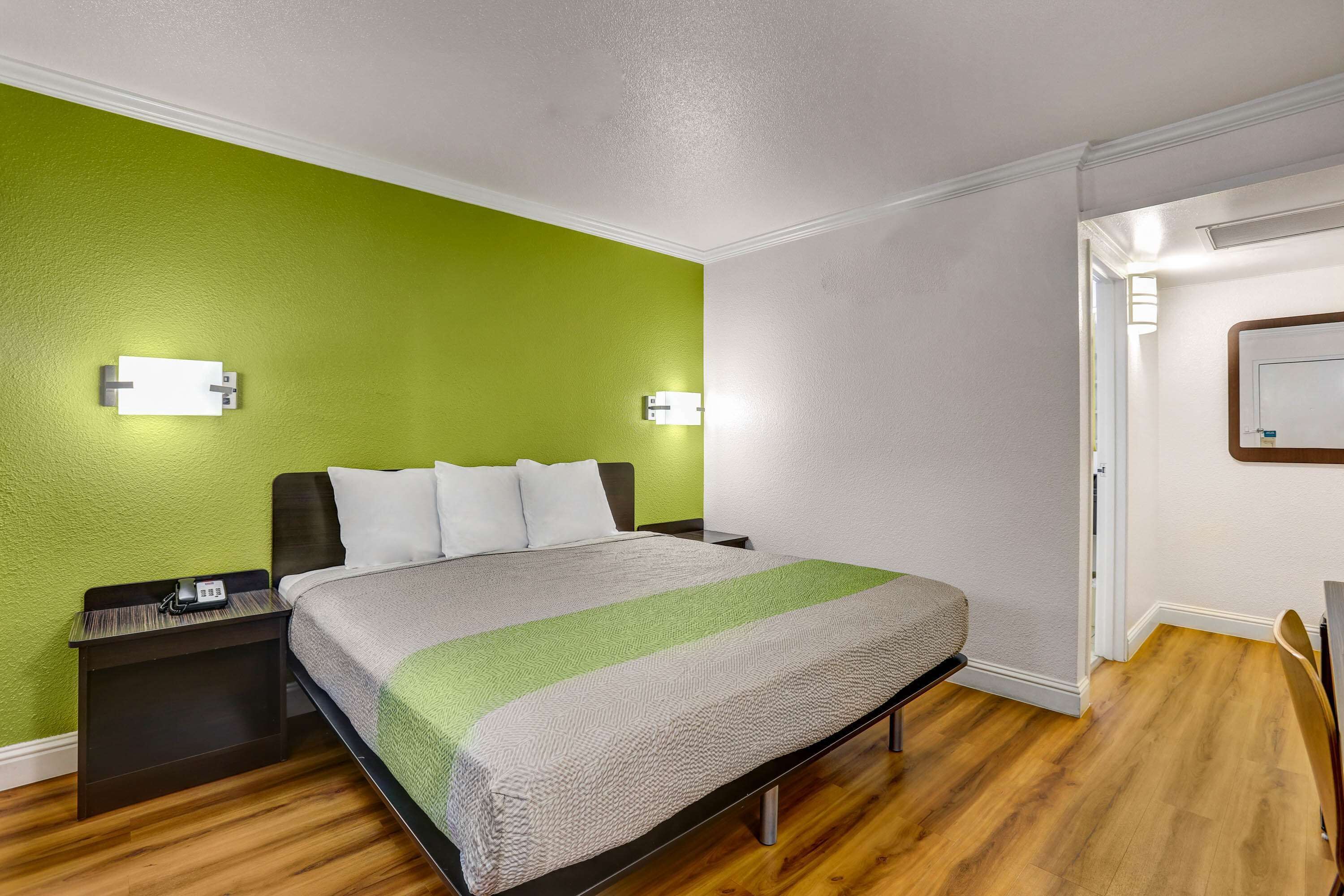 A hotel room with a bed, nightstand, and bedside lamp.