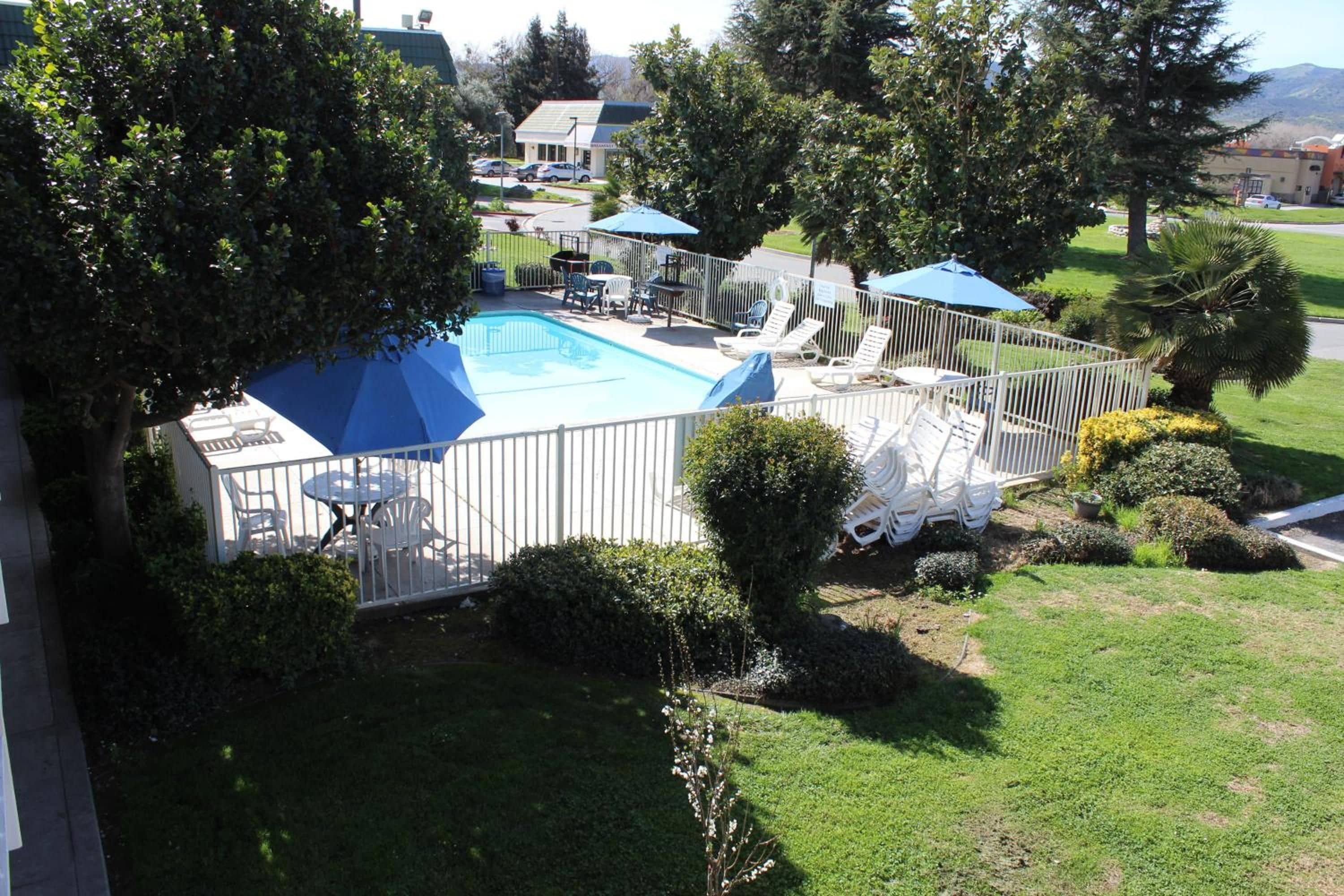 A backyard with a swimming pool, patio furniture, and a fenced area.