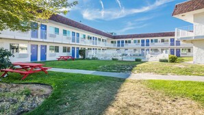 A motel with a courtyard, picnic tables, and a pool.