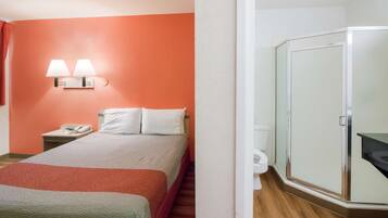 Ein Hotelzimmer mit Bett, Nachttisch mit Telefon, Wandlampe und Kleiderschrank.