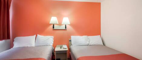 Habitación de hotel con dos camas, una mesita de noche y dos lámparas de pared.
