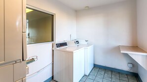 A laundry room with a washing machine and dryer, a window, and a tiled floor.