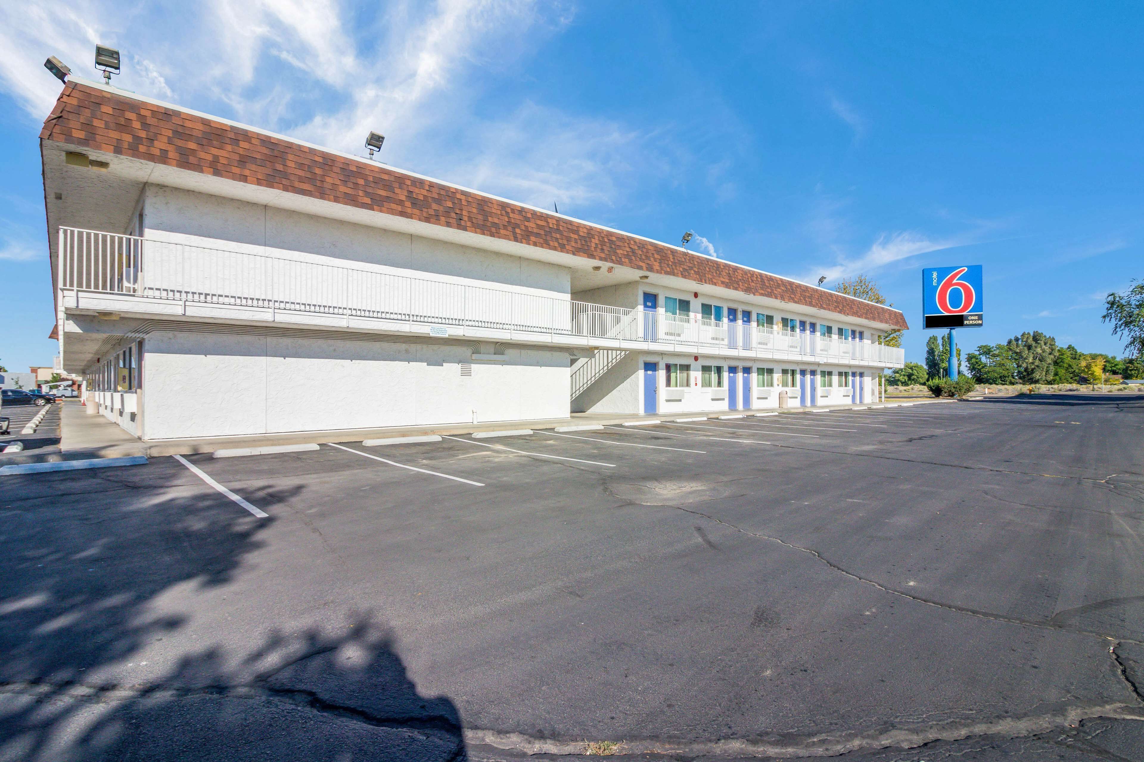 A motel with a brick roof, multiple balconies, and a parking lot.