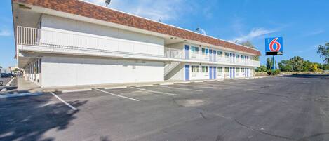 A motel with a brick roof, multiple balconies, and a parking lot.